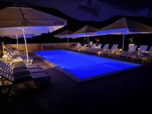 a swimming pool with chairs and umbrellas at night at Pension Riviera-Šilo in Šilo