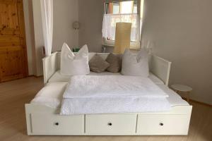 ein weißes Bett mit Kissen auf dem Zimmer in der Unterkunft Ferienhaus Bärbelstein / Wohnung Bärbelstein in Erlenbach