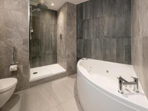 ein Badezimmer mit einer Badewanne, einem WC und einem Waschbecken in der Unterkunft voco Edinburgh - Haymarket, an IHG Hotel in Edinburgh