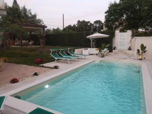 a swimming pool with chairs and a table and an umbrella at Villa Grazia in Fondachello