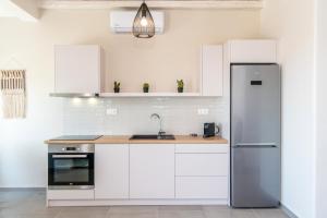 a kitchen with white cabinets and a stainless steel refrigerator at Porto Bello Tinos in Agios Ioannis