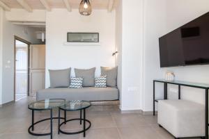 een woonkamer met een bank en een tv bij Porto Bello Tinos in Agios Ioannis