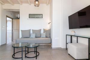 a living room with a couch and a tv at Porto Bello Tinos in Agios Ioannis