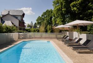 a swimming pool with lounge chairs and an umbrella at Le Monde de Charlie in Vichy
