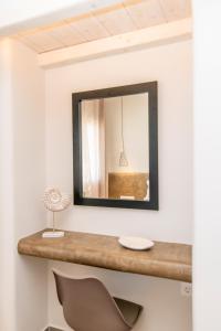 a mirror on the wall of a room with a chair at Porto Bello Tinos in Agios Ioannis
