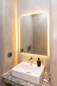 a bathroom with a white sink and a mirror at Porto Bello Tinos in Agios Ioannis