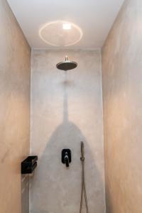a bathroom with a shower with a light on the ceiling at Porto Bello Tinos in Agios Ioannis