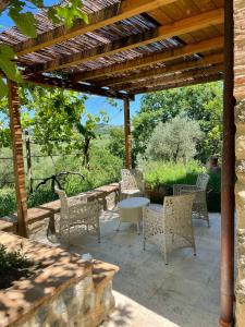 un patio con mesa y sillas bajo una pérgola de madera en Agriturismo Alchimista, en Casole dʼElsa