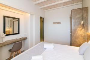 a bedroom with a white bed and a chair at Porto Bello Tinos in Agios Ioannis