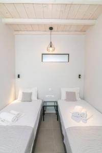 two beds in a room with white walls at Porto Bello Tinos in Agios Ioannis