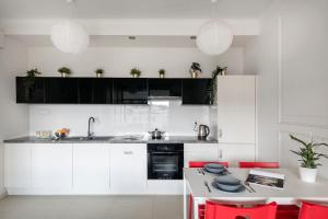 cocina con armarios blancos y detalles en rojo en Waw - Apartamenty Wilanów II Sarmacka, en Varsovia