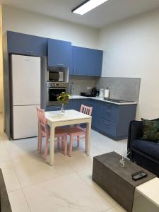 cocina con mesa, sillas y armarios azules en PORT CITY HAIFA - Luxury Apartments 50 mtrs From The Beach, en Haifa