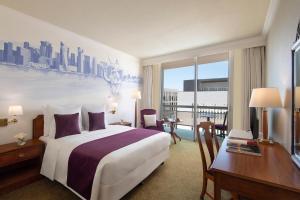 Treffen House Doha - Souq Waqif and next to Msheireb Metro Station في الدوحة: غرفة فندقية تحتوي على سرير كبير ومكتب وطاولة
