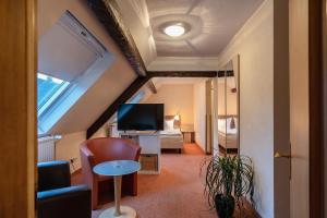 ein Wohnzimmer mit einem TV und ein Zimmer mit einem Bett in der Unterkunft Hotel Altes Weinhaus in Neustadt an der Weinstraße