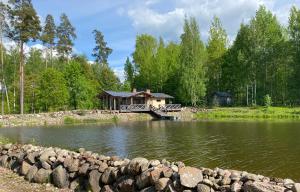 a house in the middle of a lake with a bridge at Dzirnavas Pirtsmāja in Cesvaine