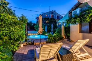 eine Terrasse mit 2 Stühlen, einem Sonnenschirm und einem Pool in der Unterkunft Regina Apartments in Brodarica