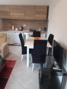 a dining room with a table with chairs and a television at Macko, Apartmani in Tivat