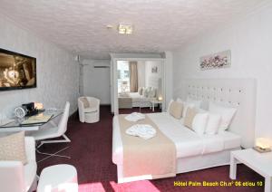 sypialnia z dużym białym łóżkiem i biurkiem w obiekcie HOTEL PALM BEACH w Cannes