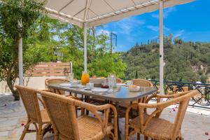 einen Tisch mit Stühlen und einem Sonnenschirm auf einer Terrasse in der Unterkunft Avrochares Villa in Zakynthos