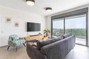 Stunning 4-bedroom Apartment Next to Achziv Beach by Sea N' Rent في نهاريا: غرفة معيشة مع أريكة كبيرة وتلفزيون