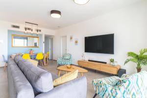 Stunning 4-bedroom Apartment Next to Achziv Beach by Sea N' Rent في نهاريا: غرفة معيشة مع أريكة وتلفزيون بشاشة مسطحة