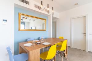 a dining room with a wooden table and yellow chairs at Stunning 4-bedroom Apartment Next to Achziv Beach by Sea N' Rent in Nahariyya