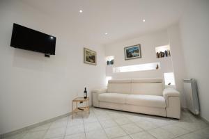 sala de estar con sofá blanco y TV de pantalla plana en Casa Elia: Locazione Breve, en Noto