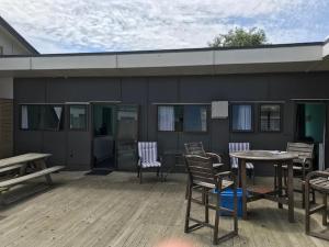 een patio met stoelen en een tafel en een gebouw bij Kiwi Cabins in Tapu