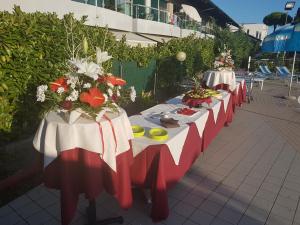 una fila de mesas con comida y flores. en Oasi Verde, en Lido di Jesolo