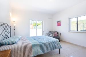 a white bedroom with a bed and a chair at Villa Flavia in Aljezur