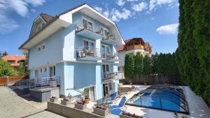 a large white house with a swimming pool at Blue Mediterran Apartment House in Balatonfüred