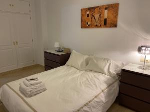 - une chambre avec un lit et des serviettes dans l'établissement Apartamento Adimar, à San Luis de Sabinillas