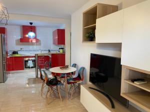 cocina con armarios rojos, mesa y sillas en Apartamento Adimar en San Luis de Sabinillas