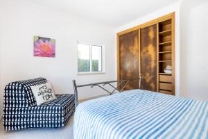 a bedroom with a bed and a chair at Villa Flavia in Aljezur