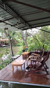 a deck with two chairs and a table and a bench at Aple Homestay in Amphawa