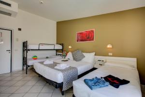 Habitación con 3 camas y mesa. en Hotel Christian Ideale Per Famiglie, en Riccione