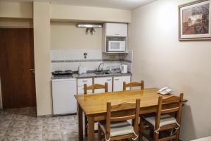eine Küche und ein Esszimmer mit einem Holztisch und Stühlen in der Unterkunft Patio Mediterraneo Apart Hotel in San Rafael