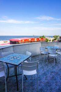 a patio with tables and chairs and the ocean at Vila Gladiola in Eforie Nord