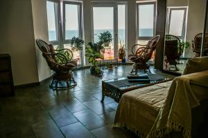 a living room with chairs and a couch and windows at Vila Gladiola in Eforie Nord