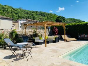 a patio with a table and chairs next to a pool at Aux Berges du Libre in Félines-Termenès