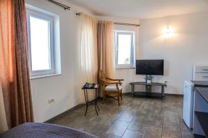 a living room with a television and a chair in a room at Vila Gladiola in Eforie Nord