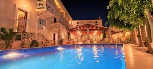 a swimming pool in front of a building at night at Kastro Hotel in Spetses