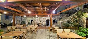 a restaurant with wooden tables and chairs and a stone wall at Kastro Hotel in Spetses