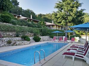 einen Pool mit Stühlen und Sonnenschirmen neben einem Gebäude in der Unterkunft Le Domaine de Gattières in Gattières