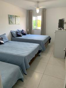 een slaapkamer met 2 bedden en een tv. bij Golden Lake in Arraial do Cabo