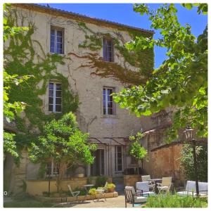a building with chairs and tables in front of it at La Vigneronne des Costières in Vauvert