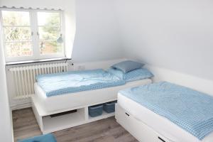 1 dormitorio con 2 camas y ventana en Haus Frisia Ferienwohnung Frisia 5, en Norddorf