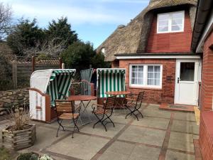 un patio con sillas y mesas frente a una casa en Haus Frisia Ferienwohnung Frisia 5, en Norddorf