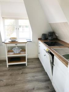 cocina con armarios blancos y encimera en Haus Frisia Ferienwohnung Frisia 5, en Norddorf