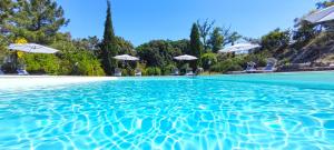 a pool with blue water and white umbrellas at Agriturismo e Maneggio Poggio Leone in Gambassi Terme